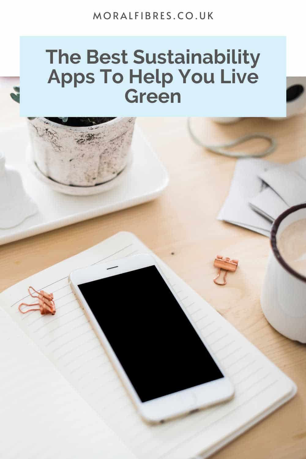 Smartphone sitting on a notebook with a blue text box that reads the best sustainability apps to help you live green.