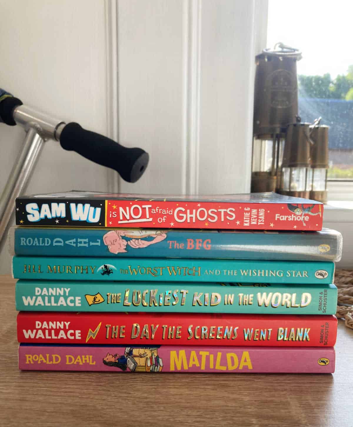 Pile of children's books on a wooden table.